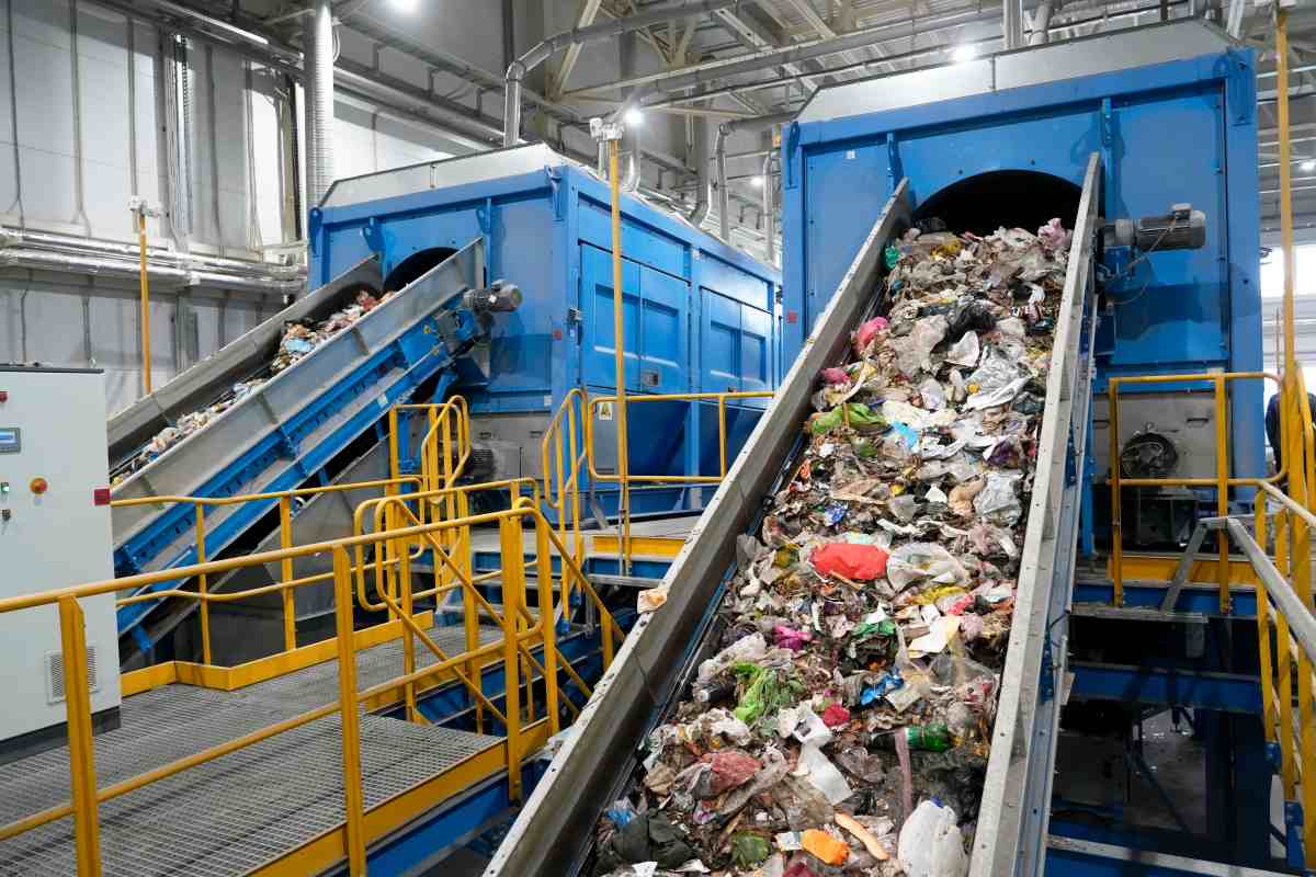 A waste sorting facility operates by separating various types of refuse for recycling. Conveyors carry debris, showcasing an assortment of discarded materials in a clean industrial environment.