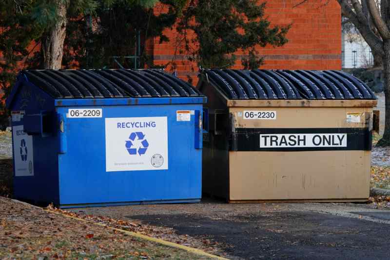 Two large commercial dumpsters, one blue for Recycling and one tan for Trash Only