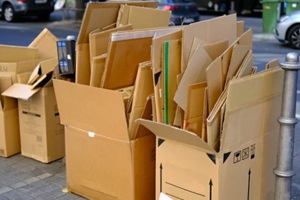 broken cardboard boxes with waste paper, next to paper recycling bin recycling problem