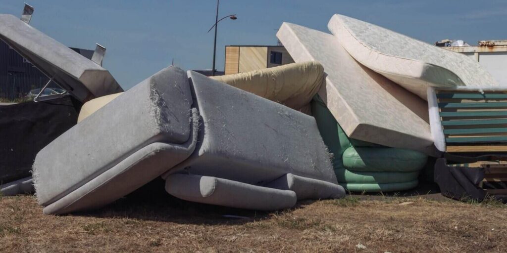 dirty used mattresses and a sofa are dumped in a landfill