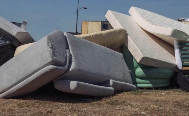 dirty used mattresses and a sofa are dumped in a landfill