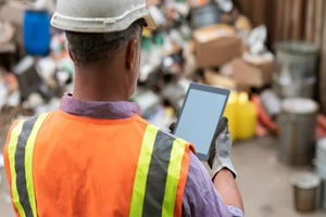 industrial worker in protective gear analyze data on digital tablet at commercial waste management facility