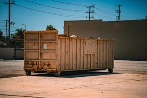 large industrial roll-off dumpster container sits in an empty lot